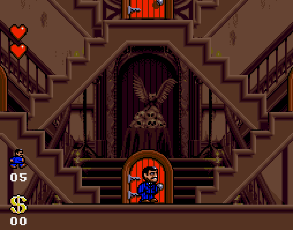 Capture : Gomez devant une porte rouge au pied d'un grand escalier double, sur un décor de hall brun orné d'un hibou et de crânes