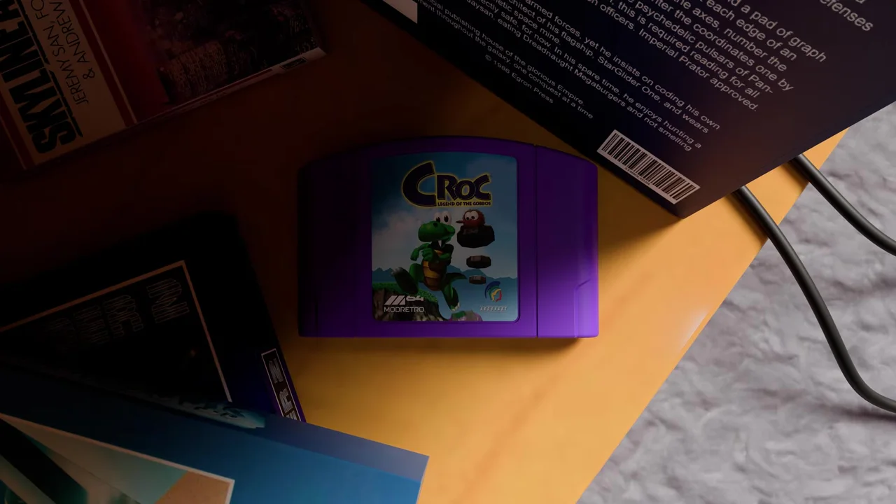 Image de la vidéo d'Argonaut : une cartouche violette étiquetée Croc Legend of the Gobbos, avec les logos M64, ModRetro et Argonaut, posée sur un bureau