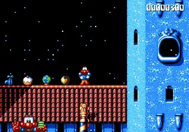 Capture de James Pond 2 - Codename: RoboCod : le héros, un poisson dans une combinaison rouge et bleue, debout sur un toit de tuiles rouges sous un ciel étoilé, à côté de plusieurs objets alignés, avec une tour bleue à droite et le score en haut de l'écran
