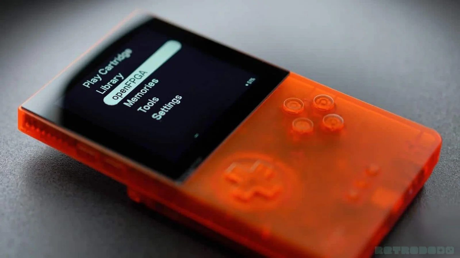 Une console Analogue Pocket de couleur orange posée sur un fond neutre