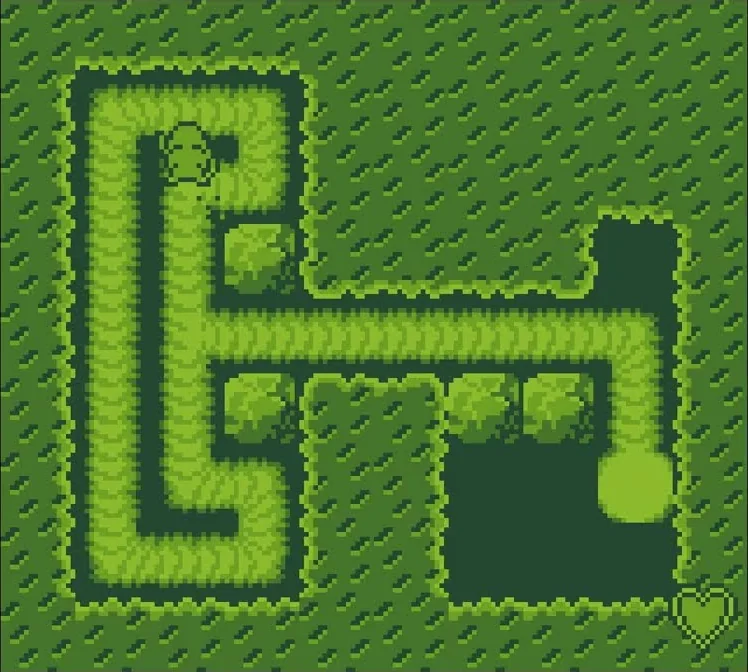 Capture de Mole Mania sur Game Boy : un labyrinthe de haies vu de dessus, des blocs de feuillage, des zones sombres, une grosse boule claire et un cœur dans un coin