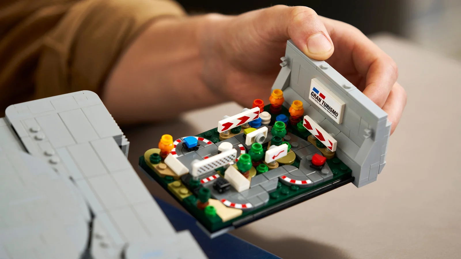 Le diorama Gran Turismo retiré de la console, tenu à la main, avec son circuit miniature et sa plaque Gran Turismo