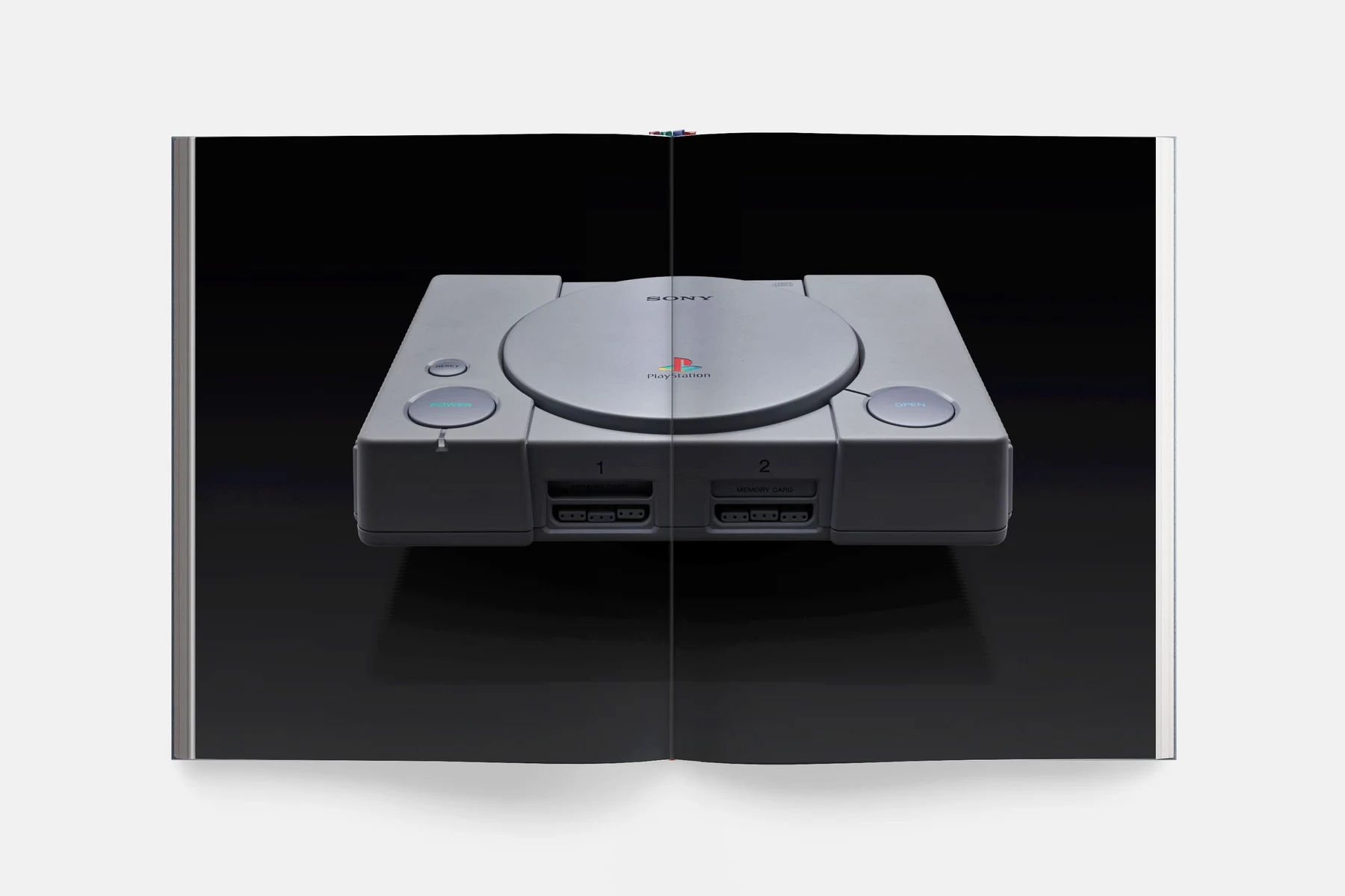 Double page du livre : une PlayStation grise photographiée sur fond noir