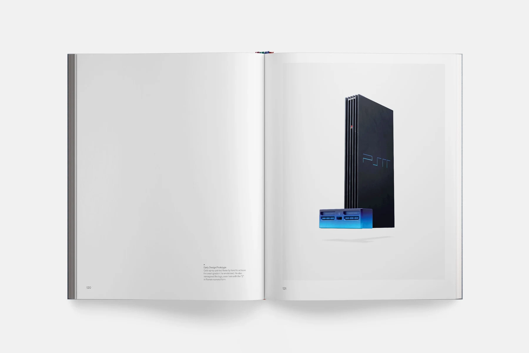 Double page du livre : un prototype de PlayStation 2 noir posé debout, avec devant lui un module bleu à fentes de cartes mémoire, sur fond blanc