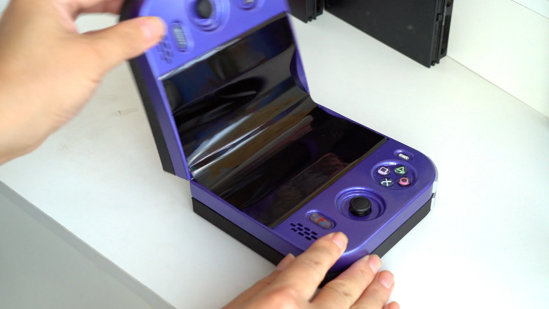 La console bleue à demi pliée sur une table, l'écran courbé entre les deux moitiés