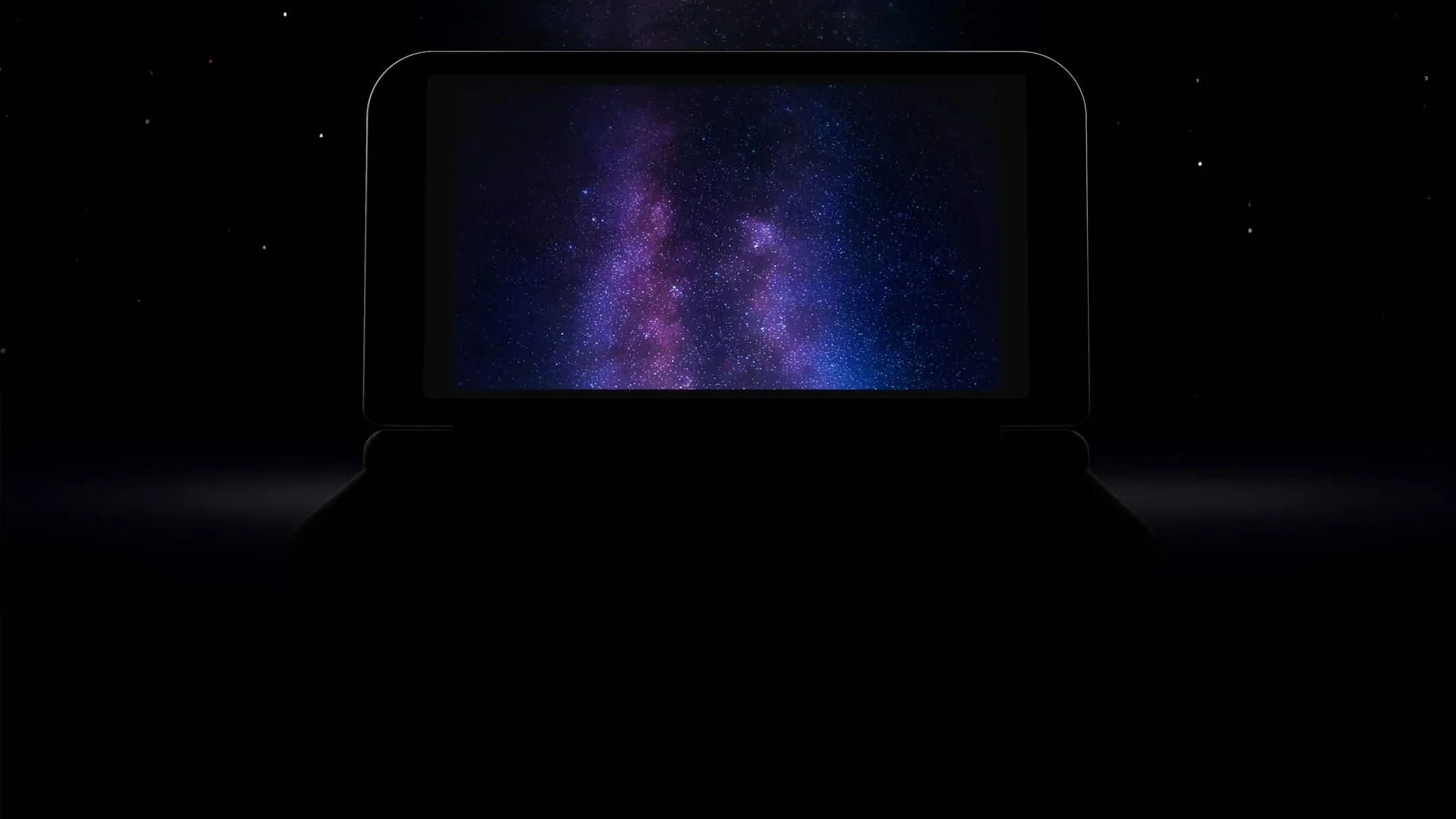 Silhouette sombre d'une portable à deux écrans, dont l'écran visible affiche un fond étoilé violet et bleu façon voie lactée, sur fond noir constellé d'étoiles