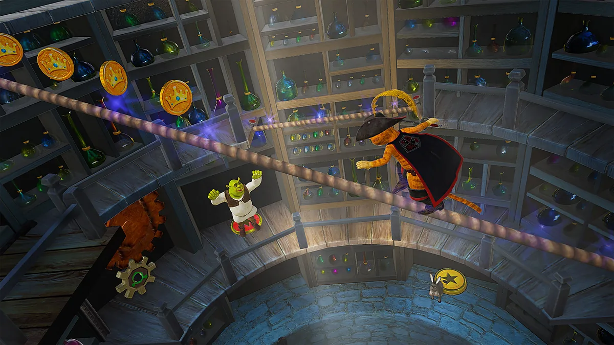 Capture de Shrek 2 Remastered : un chat botté, chapeau à plume et cape noire, avance sur une corde tendue au-dessus d'une pièce circulaire garnie d'étagères de fioles, près de pièces dorées