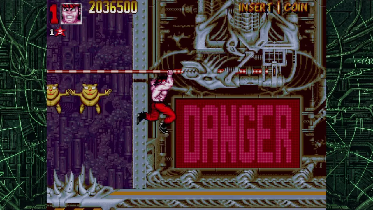 Capture : le héros suspendu à une barre devant un grand panneau rouge marqué DANGER, dans un décor mécanique gris