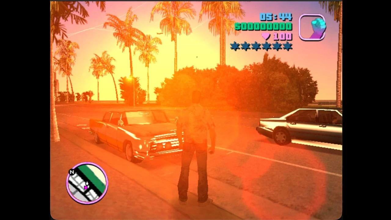Capture d'écran du port GameCube de GTA Vice City montrant une rue bordée de palmiers au coucher du soleil, avec l'interface de jeu (argent, vie, étoiles de recherche) à l'écran