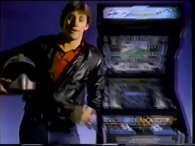 Image de la publicité : un jeune homme en blouson de cuir, casque à la main, devant une borne d'arcade Xevious