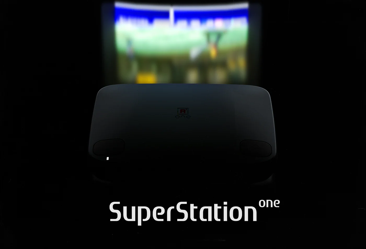 La console SuperStation One posée devant un téléviseur affichant un jeu PlayStation flouté, avec son nom en toutes lettres