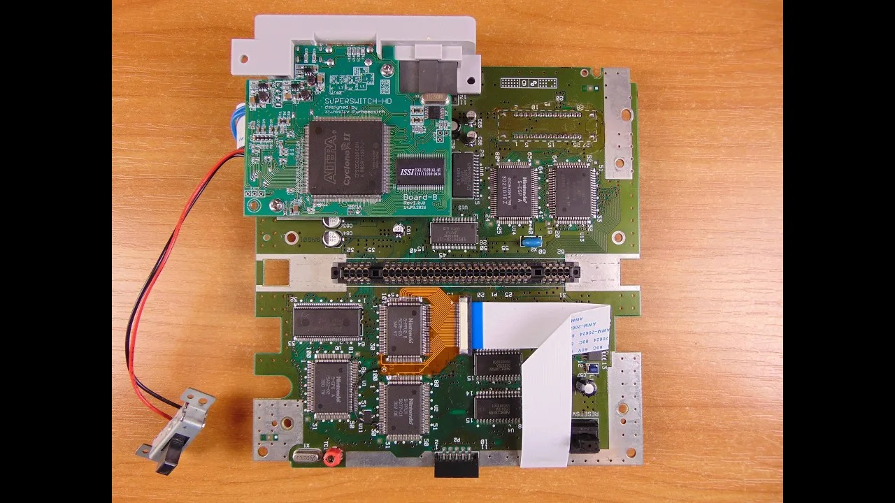 Vignette de la vidéo : une carte mère de Super Nintendo équipée de la carte Superswitch HD, d'un adaptateur souple orange et d'une nappe blanche